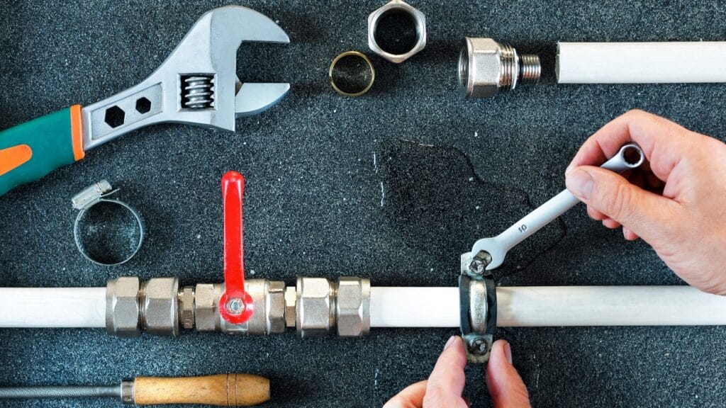 Plumber repairing a pipe valve with an adjustable wrench in Casa Grande