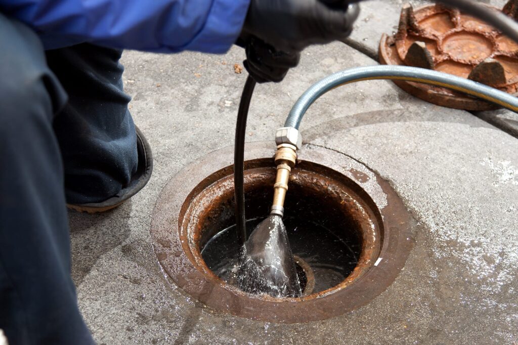 Plumber hydro jetting a sewer line through a manhole in Casa Grande