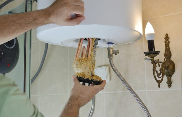 Technician removing mineral buildup from a water heater in Casa Grande